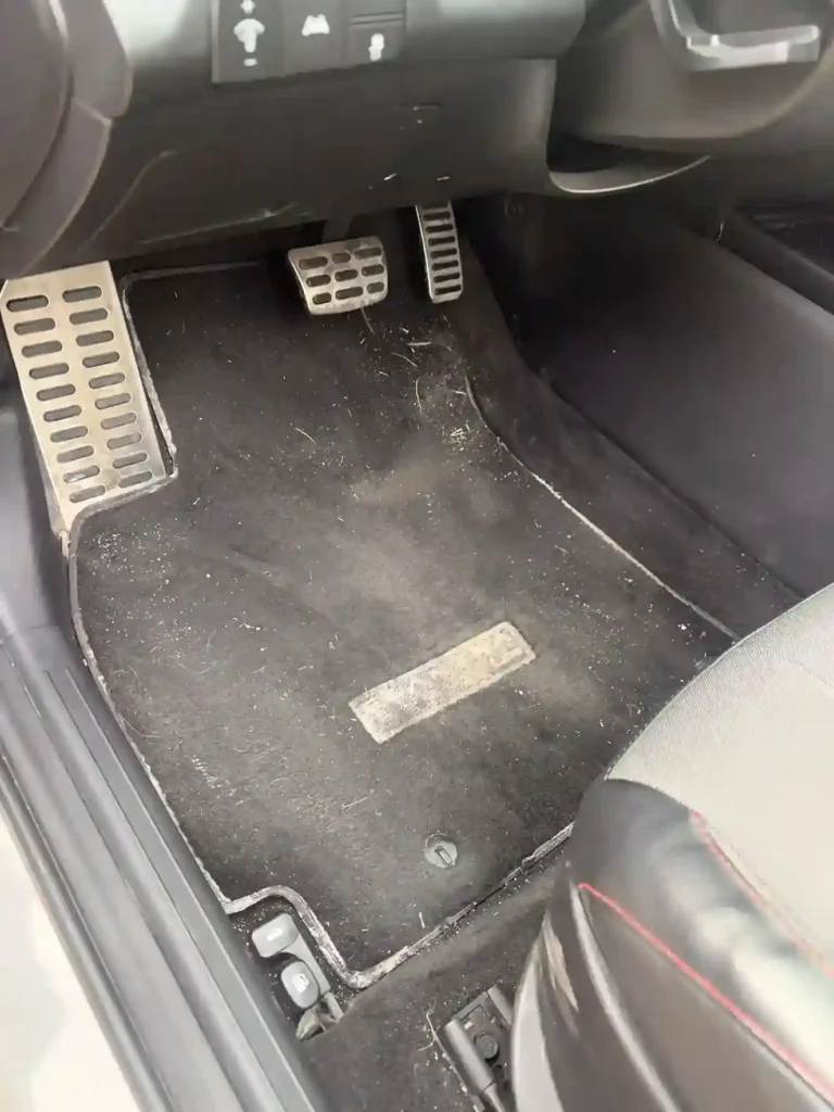 Dusty car floor mat and door sill covered in debris before deep cleaning 