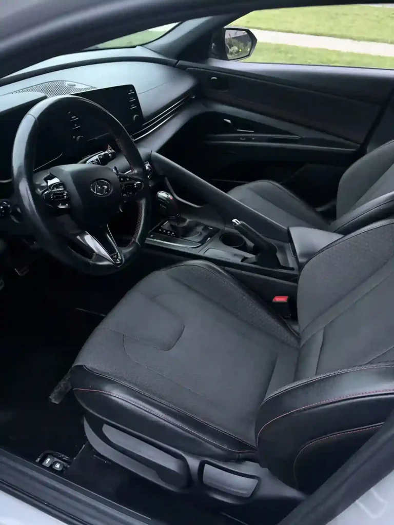 Front cabin view of a car's steering wheel, seats, and console before detailing