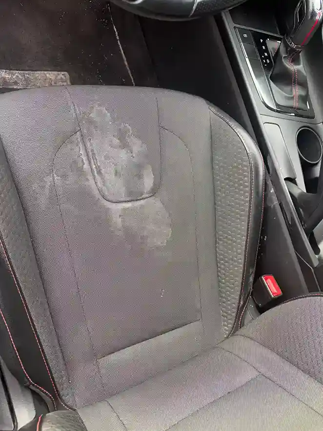 Close-up of a stained fabric car seat back before stain removal treatment 