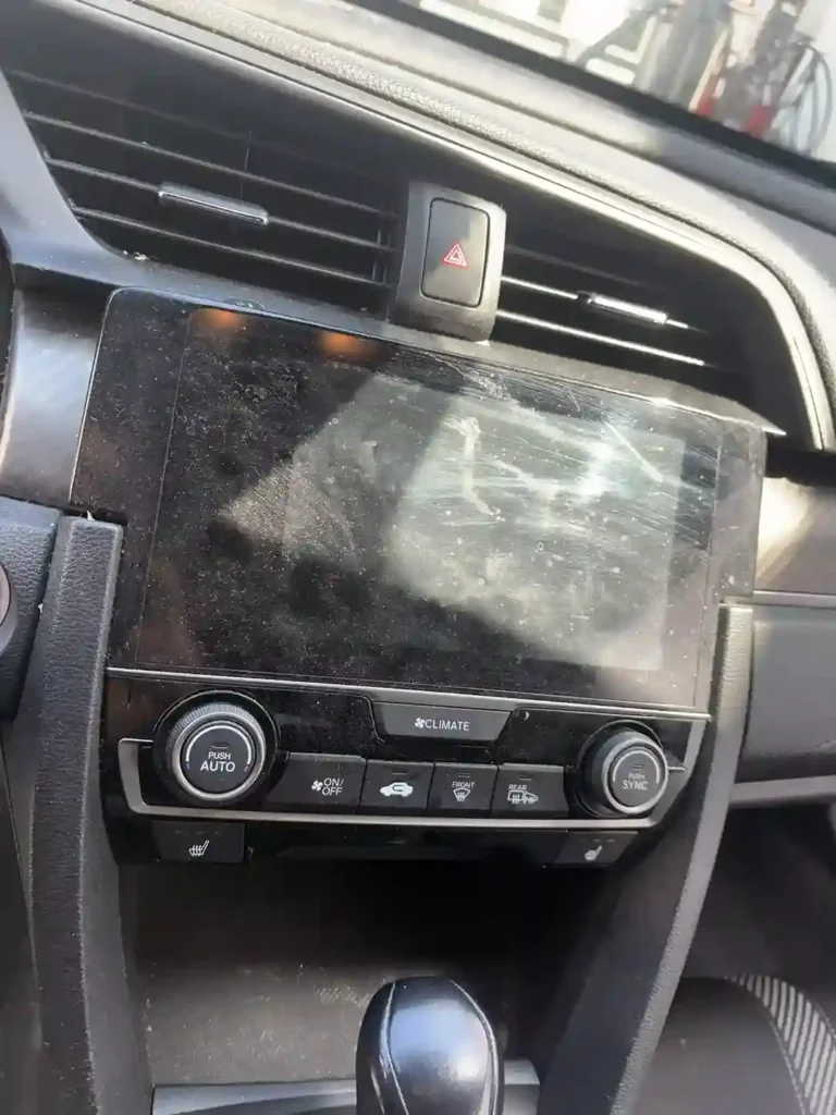 Dust-covered infotainment touchscreen and climate control panel before detailing 