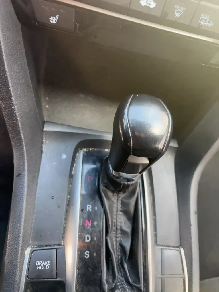 Close-up of an automatic gear shifter and dusty center console during interior detailing