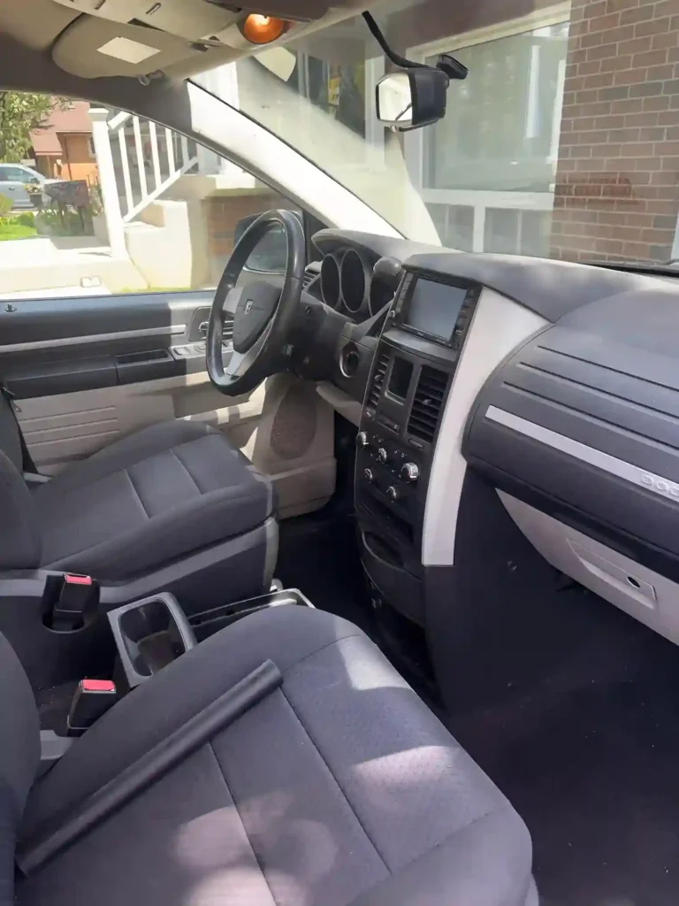 Front interior view of a minivan showing steering wheel, dashboard, and cup holders
