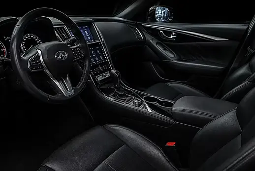 Clean black leather interior of an Infiniti Q60 showing steering wheel, dashboard, and center console