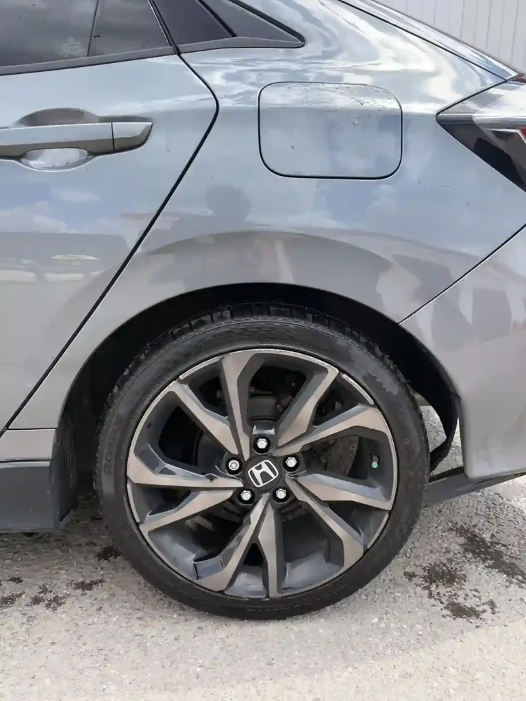 Freshly detailed alloy wheel and glossy tire on a gray sedan